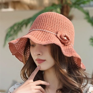 Orange hollow knit sun hat with wavy brim and floral decor for outdoor beach vacations