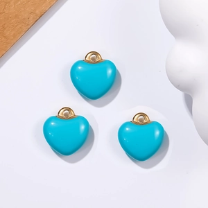 Three turquoise heart charms with gold loops for DIY jewelry making on white background