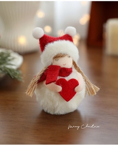 Detail of plush snowman ornament with red heart on a rustic wooden table under warm bokeh
