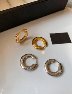 Detailed view of thick gold and silver hoop earrings with marquise-cut zircon accents