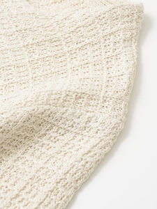 Macro shot of textured off-white waffle knit fabric showing fine craftsmanship