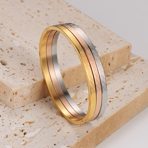 Three-tone stainless steel bangles with textured spiral design on beige stone