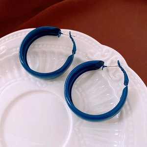 Macro shot of large navy blue enamel hoop earrings on a white vintage ceramic tray