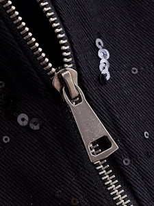 Macro view of vintage metal zipper on black ribbed fabric with sequin details
