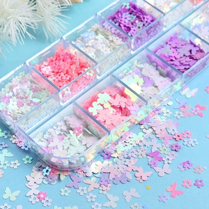 Macro shot of 12-grid box with iridescent flower and butterfly nail art sequins