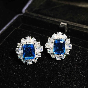Macro detail of rectangle blue sapphire earrings with white zircon on black velvet