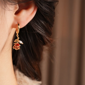 Gros plan de boucles d'oreilles rose en émail rouge avec placage or sur un mannequin