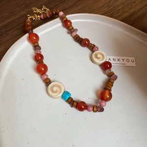 Vintage stainless steel necklace with agate and wood beads on a white ceramic plate