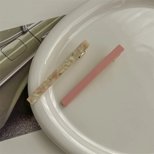 Detail view of pink and iridescent acetate hair clips on a white ceramic plate