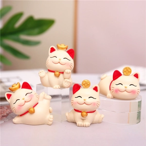 Detailed view of four cute resin lucky cat figurines on a desk with warm lighting