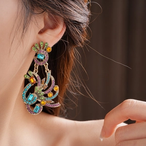 Close-up of vintage peacock earrings with multi-colored crystals on a model's ear