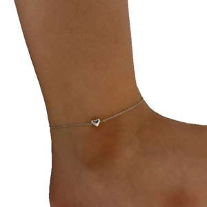 Minimalist silver stainless steel heart anklet worn on ankle against a white background