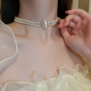 Gros plan d'un collier ras du cou double couche en perles dorées avec pendentif en cristal