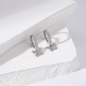Detailed view of S925 sterling silver bow earrings with pave crystals on white stone