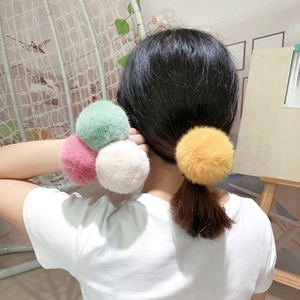 Detail of plush faux fur hair ties in pink, green, beige and yellow on a ponytail