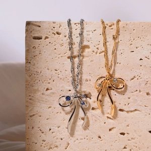 Detail of bow-shaped pendants with blue and clear zircon on gold and silver chains