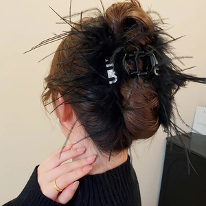 Détail d'une pince à cheveux en plumes noires de luxe avec lettre B en strass brillant