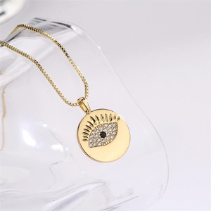 Dettaglio macro del ciondolo occhio greco dorato con zirconi e catena a maglia box