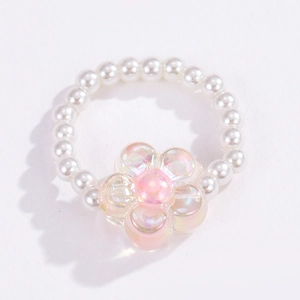 Close-up of a beaded flower ring featuring white pearls and a pink iridescent floral charm