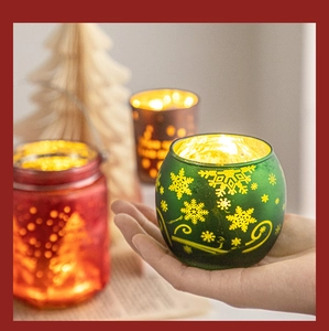 Detailed close-up of a green Christmas glass candle holder with snowflake patterns