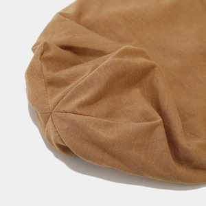 Détail macro du bonnet en tricot camel montrant les finitions de couture radiale précises