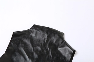 Detail of glossy black PU fabric texture with ruched pleats and reflective surface