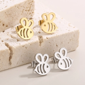 Fashionable bee stud earrings in gold and silver finish on a textured stone display