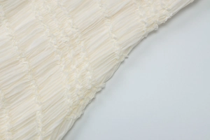 Détail macro du tissu smocké blanc cassé et texture plissée de la robe d'été