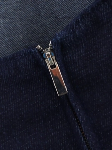 Vue détaillée du zip en métal argenté sur le tissu en denim bleu foncé de la robe courte
