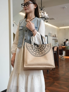 Linen tote bag with black geometric printing held by a model in a cafe setting