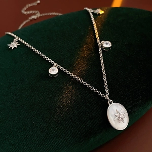 Dettaglio collana in madreperla ovale con stella di zirconi su velluto verde scuro