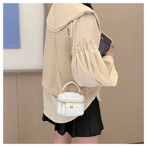 White quilted barrel chain bag with gold floral accents worn by a child model