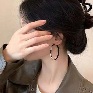 Boucles d'oreilles créoles géométriques à motif léopard portées par un mannequin en extérieur