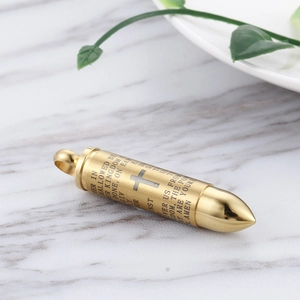Macro shot of gold bullet pendant with engraved cross and The Lord's Prayer on marble