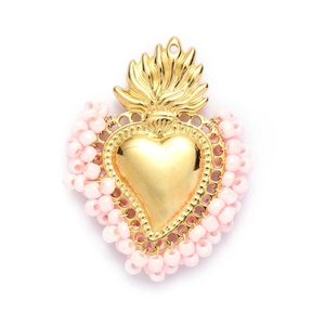 Detailed close-up of a golden sacred heart pendant surrounded by soft pink beads