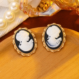 Detailed close-up of vintage cameo stud earrings with gold filigree and portrait engraving