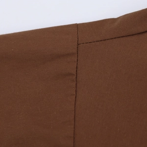 Macro shot of brown poplin fabric texture and reinforced stitching on shirt shoulder
