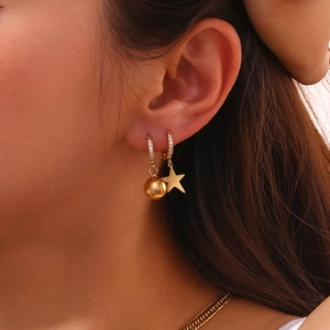 Close-up of asymmetrical 18K gold star and ball drop earrings on model's ear