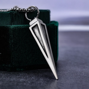 Macro shot of retro triangular pyramid steel pendant on green velvet jewelry box