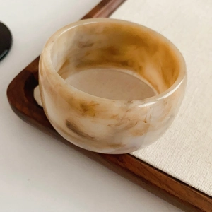 Detailed macro view of vintage marble resin ring on a warm wooden tray background