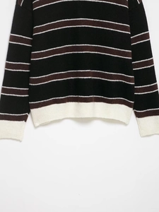Close-up of white ribbed cuffs and hem on a black and brown striped knit polo sweater