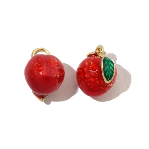 Macro detail of red strawberry enamel pendants with gold loops for DIY jewelry making