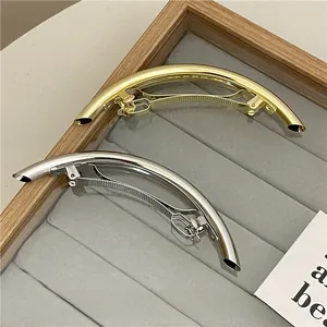 Detail view of minimalist gold and silver metallic tubular hair clips on a velvet tray
