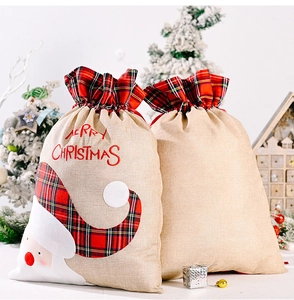 Detail of burlap Christmas gift bag with Santa Claus embroidery and plaid drawstring closure