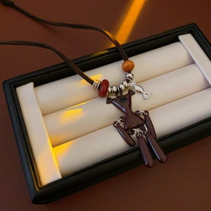 Close-up of brown bear pendant with wooden beads and leather cord on jewelry tray