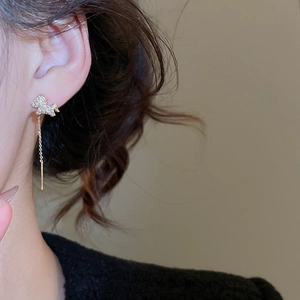 Detail of gold-plated horse earrings with long chains and sparkling rhinestones