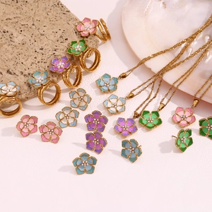 Flat lay of 18K gold floral jewelry set with colorful enamel petals and pearl accents