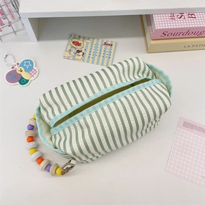 Macro view of green striped fabric tissue box with colorful bead handle on desk