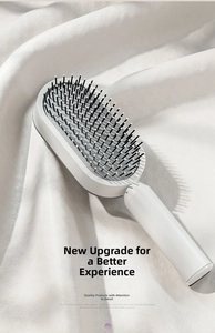 Detailed view of white massage hairbrush with soft cushion and black round tipped bristles