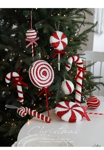 Close-up of red and white candy cane and lollipop ornaments hanging on a Christmas tree